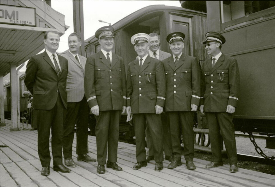 1972. Her er jernbanefunksjonærer samlet på Lomi stasjon rett før avgang med siste tog i 1972. Fra venstre stasjonsformann Terje Hansen, stasjonsbetjent Harald Karlsen, stasjonsmester Trygve Hansen, overkonduktør Einar Setså, stasjonsbetjent Agnar Bergholst, lokomotivfører Frode Setså og overkonduktør Gunnar Kvæl. Hvem fotografen var er ukjent. 1972. Her er jernbanefunksjonærer samlet på Lomi stasjon rett før avgang med siste tog i 1972. Fra venstre stasjonsformann Terje Hansen, stasjonsbetjent Harald Karlsen, stasjonsmester Trygve Hansen, overkonduktør Einar Setså, stasjonsbetjent Agnar Bergholst, lokomotivfører Frode Setså og overkonduktør Gunnar Kvæl. Hvem fotografen var er ukjent. Foto: Sulitjelma historielag