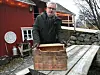 BOKKASSEN. Sverre Fjørtoft med bokkassen hvor kirkebøkene lå gjemt. Bak ham ligger låven hvor kirkebøkene hadde ligget i nær 80 år. Foto: Arild Bjørnbakk