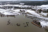 Dronebilde av rasområde ved innsjø, med ødelagt vei og jernbanespor omgitt av snødekt landskap.