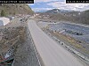 En tom veistrekning går gjennom et fjellområde med tunnel i enden og steinmasser langs veien.