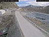 En tom veistrekning går gjennom et fjellområde med tunnel i enden og steinmasser langs veien.